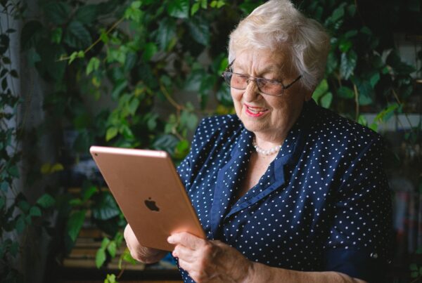 Abuela sonriendo mientras conversa por videollamada con una tableta