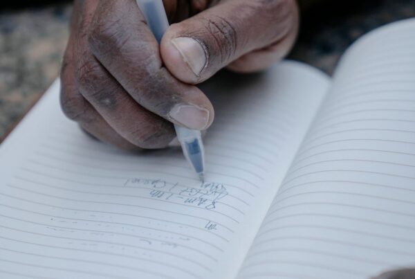 Mano de una persona mayor escribiendo en un cuaderno